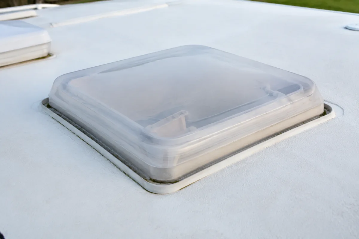 Lanterneau et joint périphérique d’une cellule de camping-car vus du toit, traces de mousse